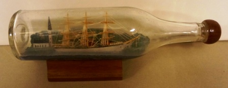 20th century sailor-made ship model housed in bottle. Depicting a fullrigged ship with church and houses. Built by Verner Höglund 1946. 