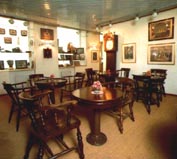 Part of a hotel's breakfast room furnished with restored 20th century ship's tables and armchairs, marine paintings and collectables.