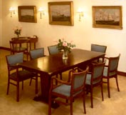 Part of a shipping company guest dining room furnished with restored 20th century original ship's dining-table, armchairs, side-table as well as original oil paintings and newly made brass lamps.