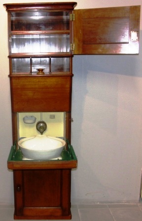 Wash cabinet in mahogany with porcelain basin and brass tap. Complete with water container, wastewater bucket and porcelain chamber pot. 