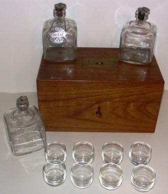 Early 20th century portable 'liquor bar' made of oak with brass handle. Containing three bottles and six glasses. 