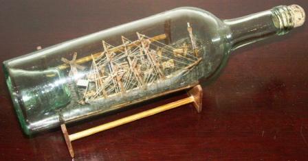 Late 19th century sailor-made ship model housed in bottle depicting a Swedish 4-masted barque. Incl wooden stand