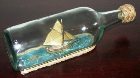 20th century ship model housed in bottle depicting "Vedjakten GRETA-LINNEA", a traditional Swedish archipelago sloop carrying wood. Signed GF (Göran Fors).