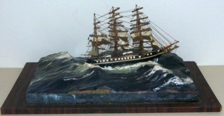20th century built waterline model depicting a full-rigged vessel in heavy sea. With working crew aloft. Signed H.B. 1968. Mounted in glass case.