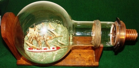Early 20th century ships in light bulb, mounted on wooden stand. With engraved brass plate documenting: "This bulb has lit Flamborough Head Light for 1,000 hrs., then taken out of service" .