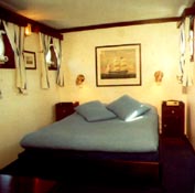 Part of a suite onboard a hotel ship, furnished with restored 20th century ship's king size bed, bedside tables, prints and newly made brass lamps.