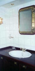 Part of a domestic bathroom furnished with restored 20th century original ship's washstand, porthole mirror and newly made brass lamp.